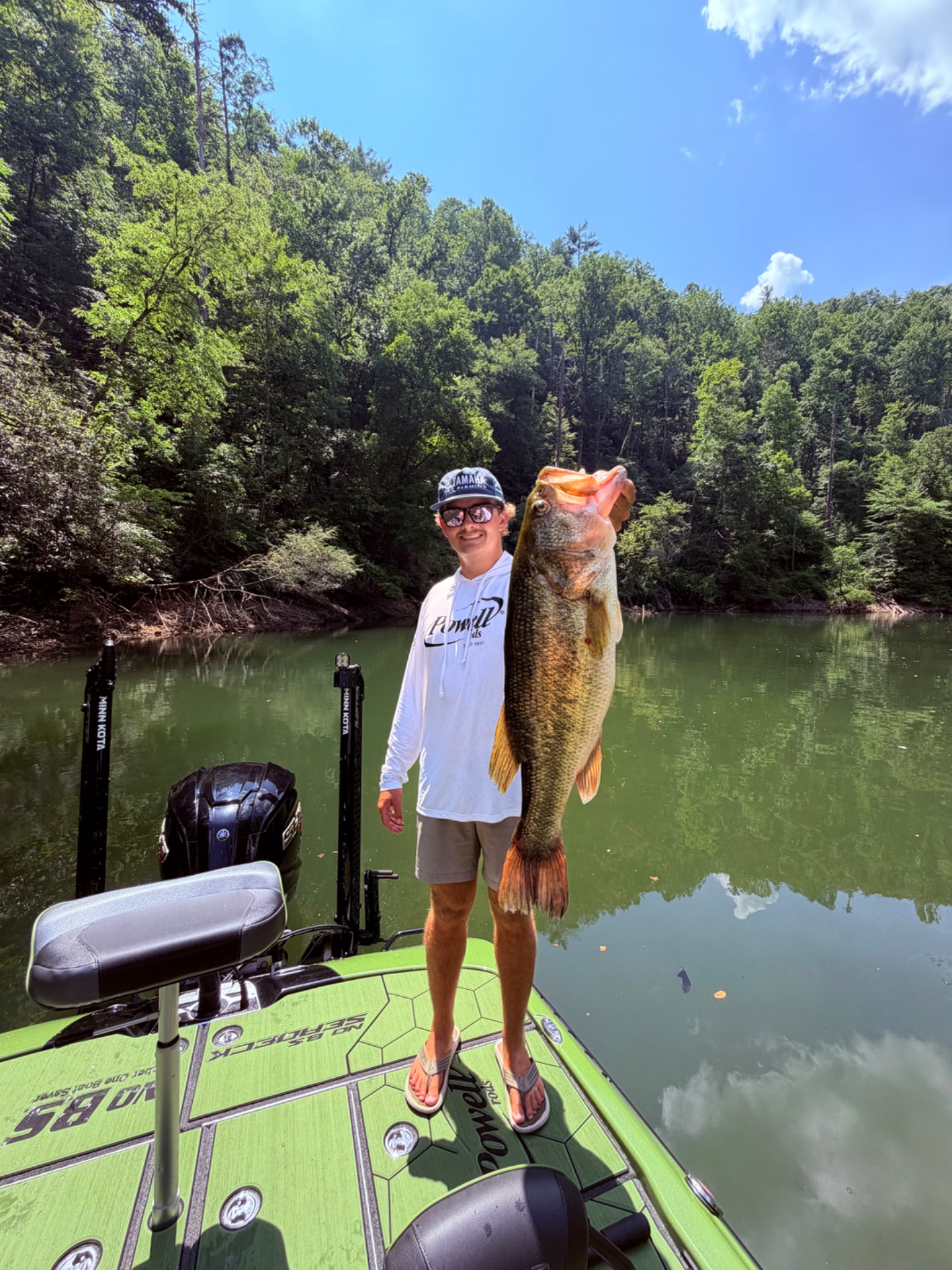 Angler holding a largemouth bass aboard a fishing boat